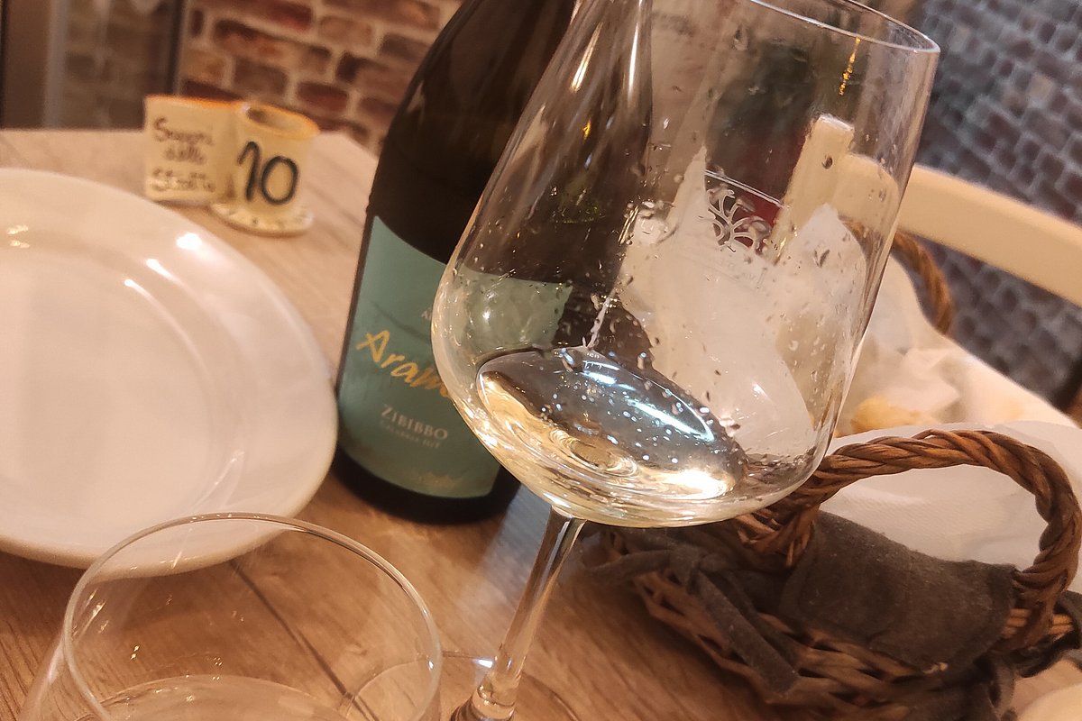 Tavola con vino Zibibbo locale e pane, muro in mattoni a vista
