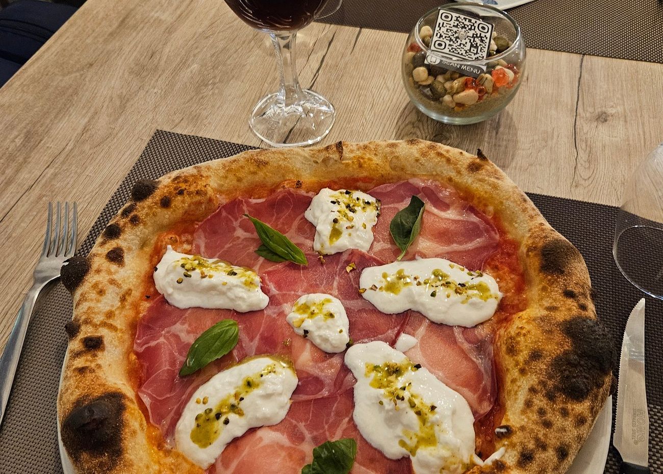 Pizza con capocollo, burrata e granella di pistacchio vista dall'alto